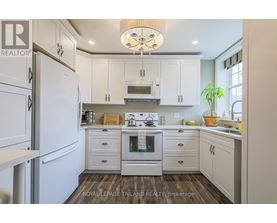 A kitchen with white cabinets and a wooden floor.
