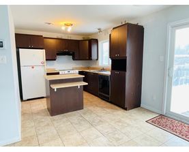 A kitchen with brown cabinets and a white refrigerator.