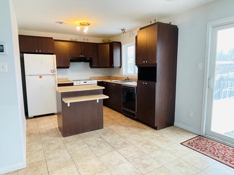 A kitchen with brown cabinets and a white refrigerator.
