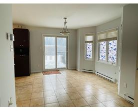 A kitchen with a refrigerator, a dining table with chairs, and a window with stained glass.