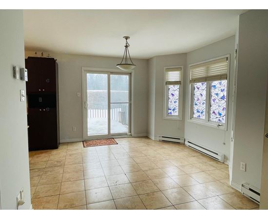 A kitchen with a refrigerator, a dining table with chairs, and a window with stained glass.