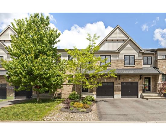 A large house with a driveway and a tree in front.