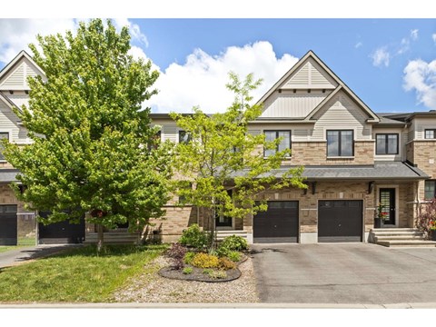 A large house with a driveway and a tree in front.