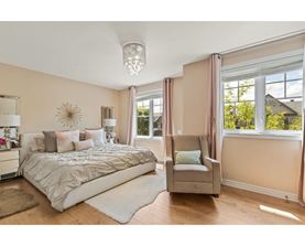 A bedroom with a large bed and a chair by the window.