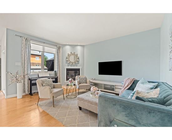 A living room with a grey couch and a fireplace.