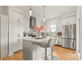 A modern kitchen with a white island and bar stool.