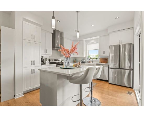 A modern kitchen with a white island and bar stool.