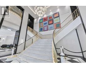 A staircase with a glass railing and a chandelier hanging from the ceiling.