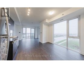A spacious, empty room with wood flooring and large windows.
