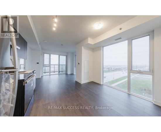 A spacious, empty room with wood flooring and large windows.