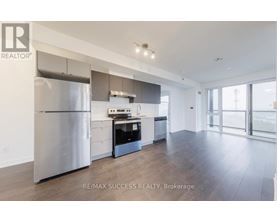 A modern kitchen with a stainless steel refrigerator and wooden flooring.