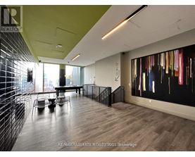 A modern office space with a long table and chairs, a staircase, and a large abstract painting on the wall.