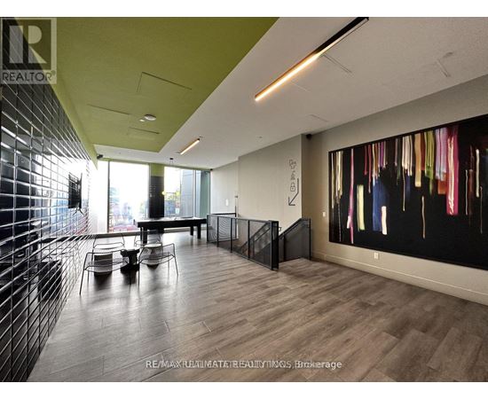 A modern office space with a long table and chairs, a staircase, and a large abstract painting on the wall.