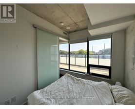 A bedroom with a large bed and a view of a parking lot through the window.
