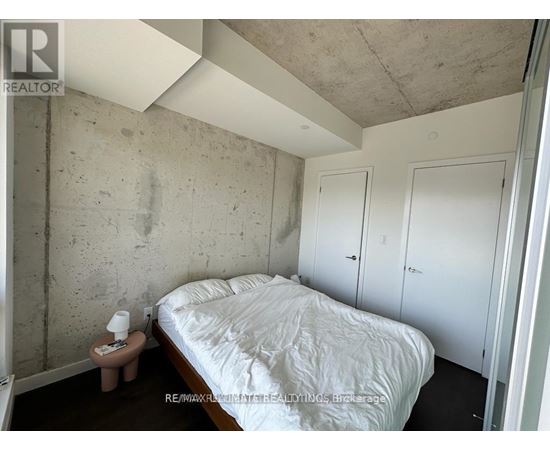A bedroom with a bed, nightstand, and two doors.