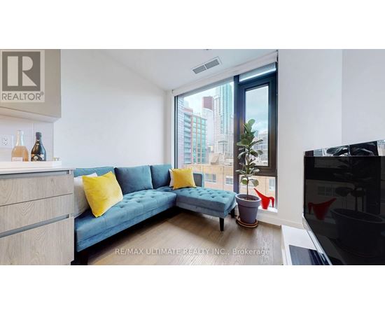 A living room with a blue couch and a large window overlooking a cityscape.