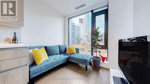 A living room with a blue couch and a large window overlooking a cityscape.
