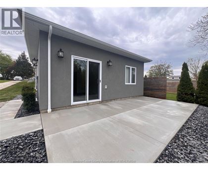 A grey house with a white door and windows is for sale.