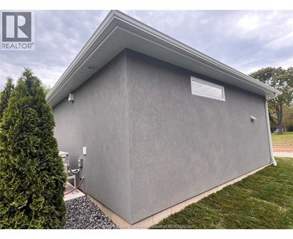 A grey building with a small window and a sign that says REALTOR.