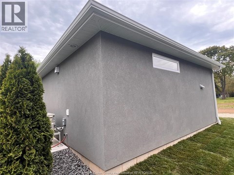 A grey building with a small window and a sign that says REALTOR.