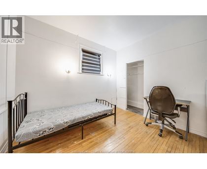 A bedroom with a bed, chair, and desk.