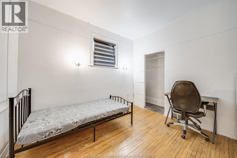 A bedroom with a bed, chair, and desk.
