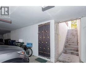 A car is parked in a garage with a bicycle leaning against the wall.