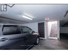 A grey car is parked in a garage with a sign that says "EXIT" above it.