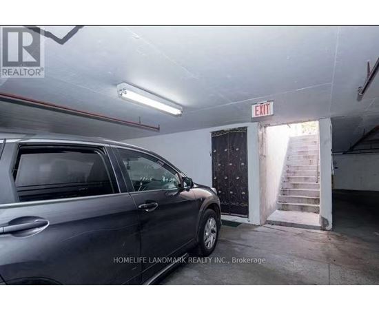 A grey car is parked in a garage with a sign that says "EXIT" above it.