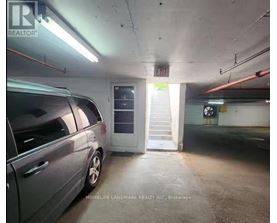 A grey car is parked in a dimly lit parking garage.