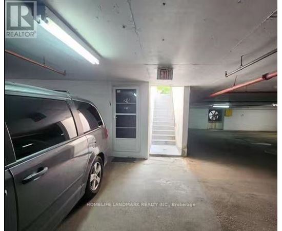 A grey car is parked in a dimly lit parking garage.