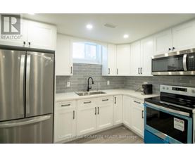 A kitchen with white cabinets and a stainless steel refrigerator.