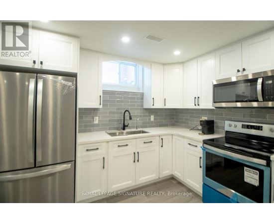A kitchen with white cabinets and a stainless steel refrigerator.
