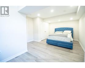A bedroom with a blue headboard bed and white walls.
