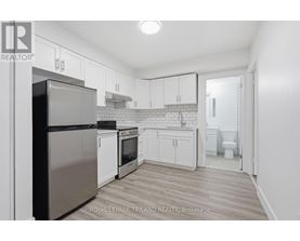 A kitchen with white cabinets and a stainless steel refrigerator.