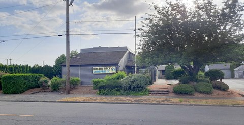 A building with a sign that says "Herbway Brewery" is surrounded by bushes and trees.