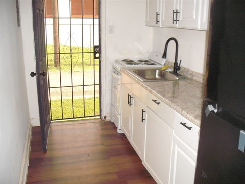 A kitchen with white cabinets and a black fridge.