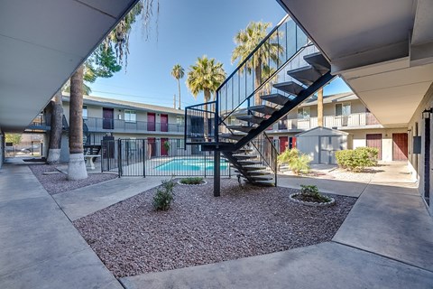 A black metal staircase with a glass balustrade leads to a pool area.