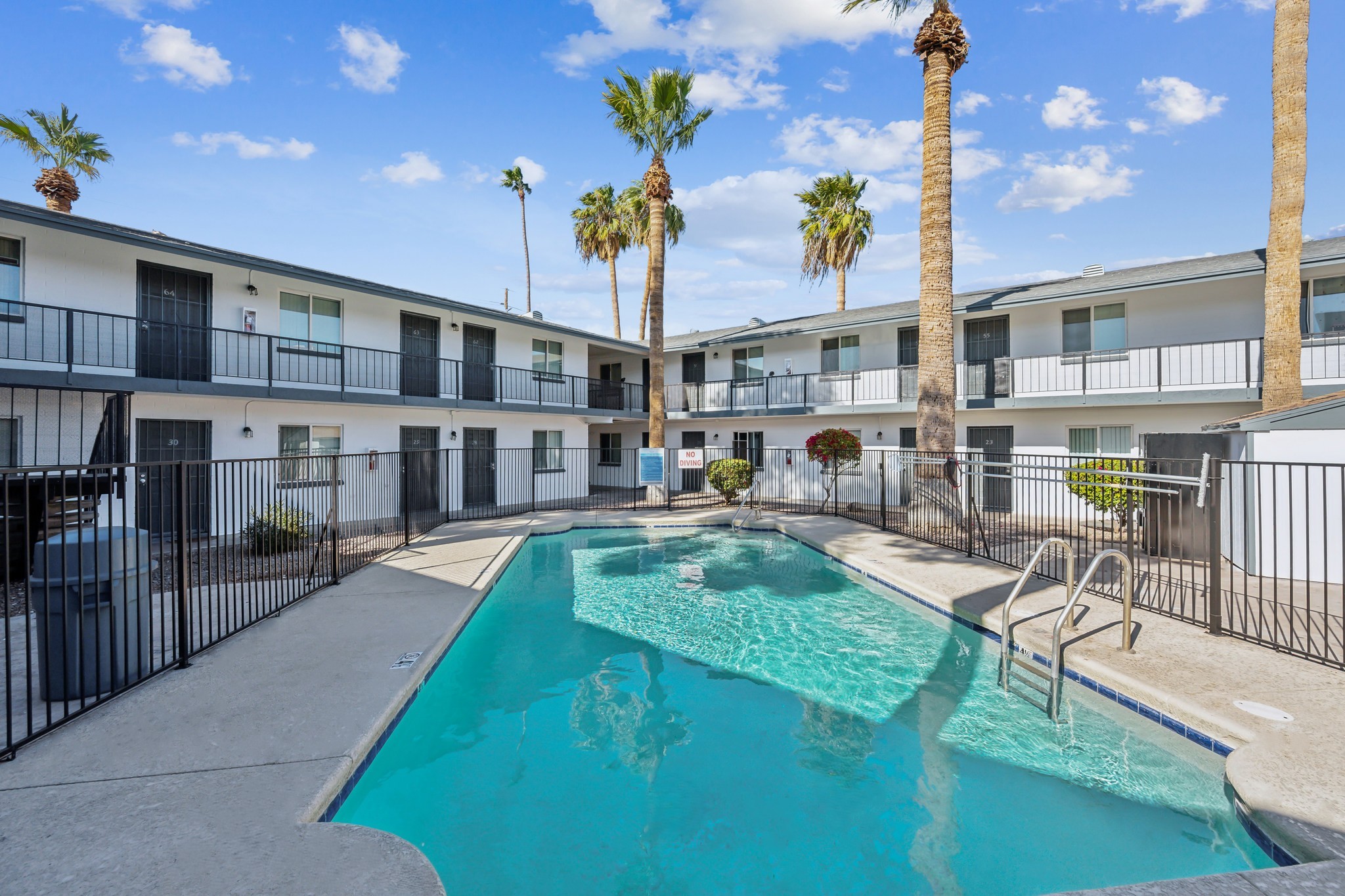 A swimming pool in front of a building with palm trees.