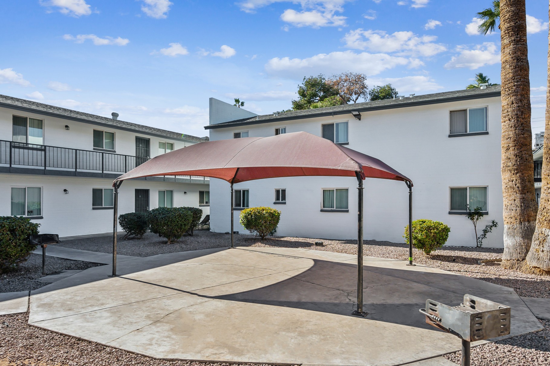 A red and white striped canopy is over a concrete patio.