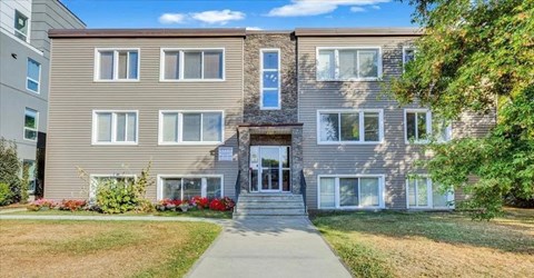 A modern two-story building with a front porch and a well-maintained lawn.