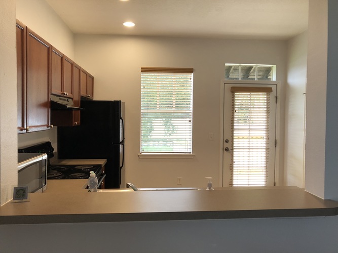 A kitchen with a black refrigerator and wooden cabinets.