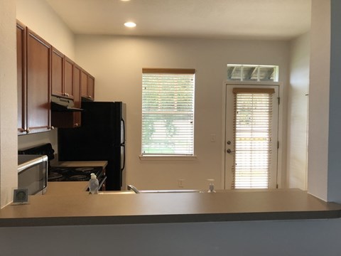 A kitchen with a black refrigerator and wooden cabinets.