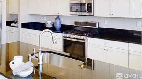 A modern kitchen with a black countertop and stainless steel appliances.