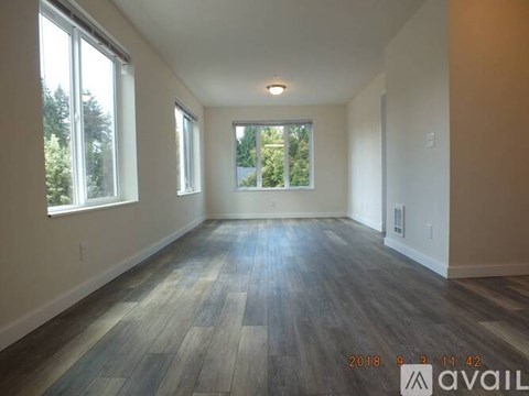 A room with wooden flooring and two windows is available for rent.
