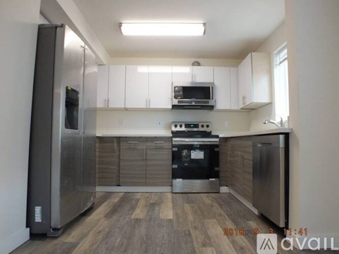 A kitchen with a refrigerator on the left and a stove top oven in the middle.