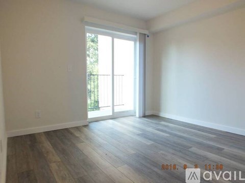 A room with wooden flooring and a sliding glass door leading outside.
