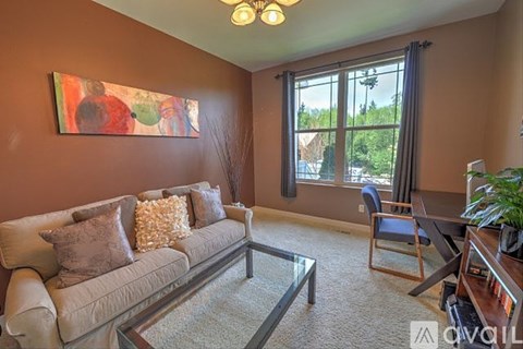 A living room with a couch, chair, and a painting on the wall.