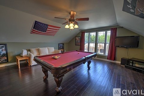 A pool table in a room with a ceiling fan and an American flag.