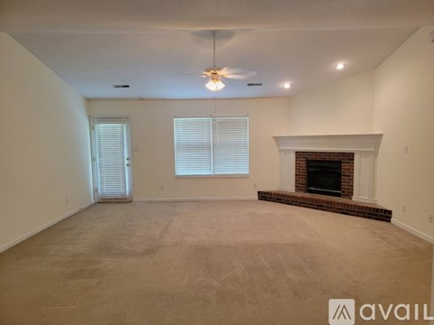 A spacious living room with a fireplace and carpeted floor.